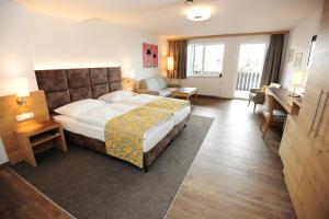 a hotel room with a large bed and a desk at Seegasthof Hois'n Wirt - Hotel mit Wellnessbereich in Gmunden