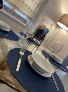 a table with plates and forks and glasses on it at Luxury Town Centre Apartment in Ipswich