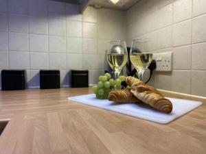 uma mesa com dois copos de vinho e croissants e uvas em Luxury Town Centre Apartment em Ipswich