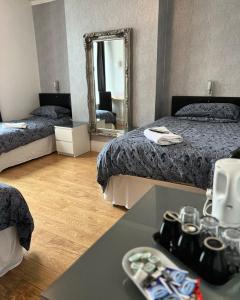 a hotel room with two beds and a mirror at parklane guest house in Cardiff