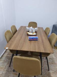 شقة مفروشة رقم 1 تبعد عن الحرم النبوي الشريف 3 كم في المدينة المنورة: طاولة خشبية عليها كراسي وعلبة طعام