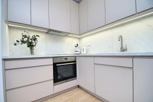 una cocina blanca con armarios blancos y un jarrón de flores en Apartament, Ceglana 76, Katowice en Katowice