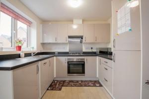 a kitchen with white cabinets and a sink and a refrigerator at Hemsworth Homestay with Double Bedroom and Private Bathroom in Hemsworth