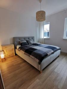 sypialnia z dużym łóżkiem i drewnianą podłogą w obiekcie Apartament Stary Tartak 11 przy ulicy 3Maja 15A w Ostródzie