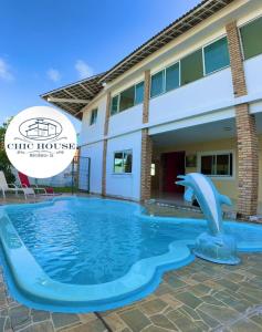 a swimming pool with a dolphin in front of a building at Chic House Suítes in Beberibe