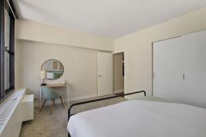 a white bedroom with a bed and a chair at Nicely Equipped 1BR Apartment Close to Shops - Chestnut 22A in Chicago