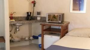 Habitación con cama y microondas sobre una mesa. en Refúgio Guest House, en Ilhabela
