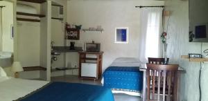 una piccola camera con letto e televisore di Refúgio Guest House a Ilhabela