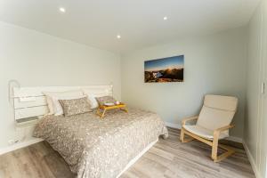 a white bedroom with a bed and a chair at Penthouse Formosa Sunset and Beach in Funchal