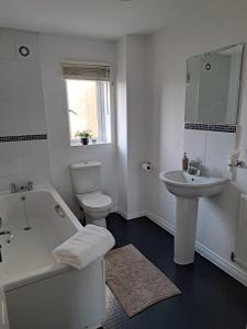 uma casa de banho branca com uma banheira e um lavatório em Large Bed in a luxuriously furnished Guests-Only home, Own Bathroom, Free WiFi, West Thurrock em Grays Thurrock