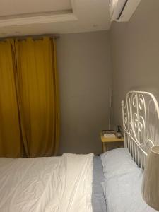 a bedroom with a white bed and a yellow curtain at AlReem Apartment in Al Madinah