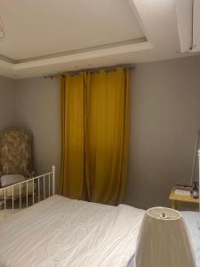 a bedroom with a bed and yellow curtains at AlReem Apartment in Al Madinah