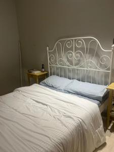 a white bed with a metal headboard in a bedroom at AlReem Apartment in Al Madinah