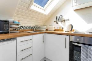 a kitchen with white cabinets and a skylight at Stylish 1 Bedroom apartment in Edinburgh