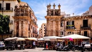 a street with tables and umbrellas in front of buildings at Massimo Luxury Rooms in Palermo