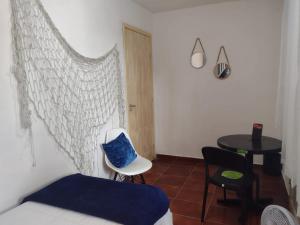 a bedroom with a bed and a chair and a table at Pousada Jardins in Macaé