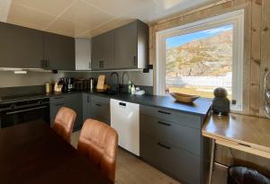 a kitchen with gray cabinets and a table and a window at Fishermans Dock Lofoten in Ballstad