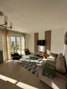 a living room with a couch and chairs and a tv at Disneyland Paris, vallée village ,Paris , villa, garden , Syline Home, 120 m2 in Serris