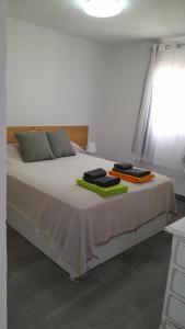 una camera da letto bianca con un letto e asciugamani di Apartamento Ilusión a Corralejo