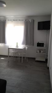 un soggiorno con tavolo, TV e finestra di Apartamento Ilusión a Corralejo