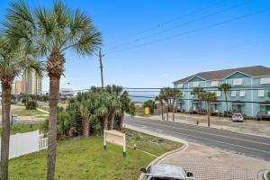 a street with palm trees and a building at Sand Castle Tower & Cabana in Panama City Beach