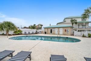 ein Swimmingpool mit zwei Stühlen und einem Haus in der Unterkunft Sand Castle Tower & Cabana in Panama City Beach