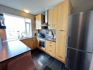 a kitchen with a stainless steel refrigerator and wooden cabinets at Cosy apartment centrally located in Reykjavik in Reykjavík