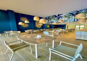 uma sala de jantar com mesas e cadeiras e pinturas na parede em FLAT 227 l Eco Resort - Praia dos Carneiros - Ao lado da Igrejinha em Tamandaré