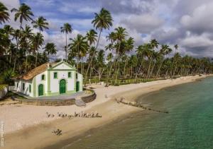 un pequeño edificio en una playa junto al agua en FLAT 227 l Eco Resort - Praia dos Carneiros - Ao lado da Igrejinha en Tamandaré