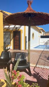 a patio with two black chairs and an umbrella at Casa Naranja in Mazarrón
