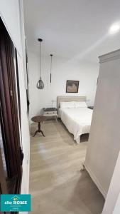 - une chambre blanche avec un lit et une table dans l'établissement 180 home Luxury Redes, à Séville