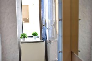 un bagno con frigorifero con due piante su un bancone di [Milan sweet home] Metro, Linate e Sky studio a Milano