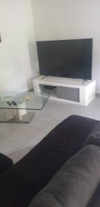 uma sala de estar com uma televisão e uma mesa de vidro em VILLA JAGUAR em Le Gosier