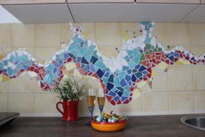 a mosaic wall in a kitchen with two wine glasses and flowers at Art house Tufi in Bistrica ob Sotli