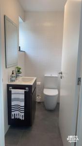 een badkamer met een toilet, een wastafel en een spiegel bij Casa Maré in Angra do Heroísmo