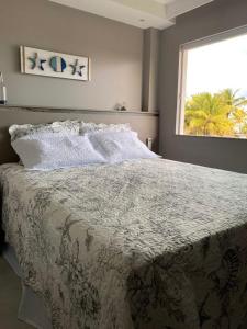 a bedroom with a large bed with a window at Cobertura Blue Beach House in Olivença