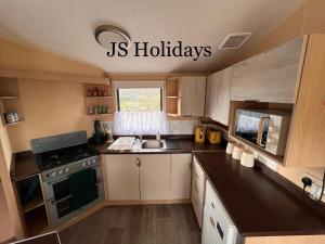 una pequeña cocina con fogones y fregadero en JS Holidays The Westmorland Lagganhouse en Ballantrae