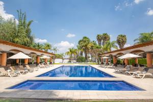 - une piscine avec des chaises et des parasols dans un complexe dans l'établissement Hotel Hacienda la Venta, à San Juan del Río