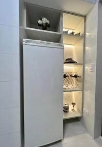 una nevera blanca en una cocina con estanterías en Flat Excepcional no Centro de Capivari en Campos do Jordão