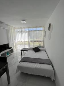 a white bedroom with a bed and a table at Apartamento con piscina y barbacoa in Cala del Moral