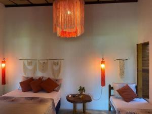 a bedroom with two beds and a table and lights at Casa do Francês in Japaratinga