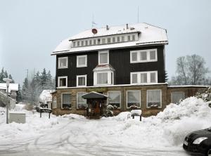 un gran edificio negro con nieve en el suelo en Haus Dümling, en Braunlage