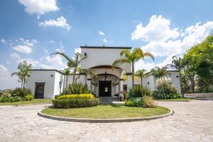 a white house with palm trees and a driveway at Hotel Hacienda la Venta in San Juan del Río