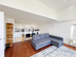 a living room with a couch and a kitchen at Portobello Dock Canalside Apartment in London