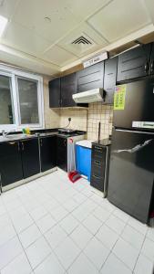 a kitchen with black cabinets and a white tile floor at Dubai Star Hostel in Dubai