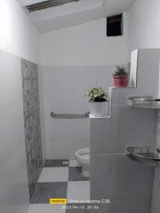 La salle de bains blanche est pourvue de toilettes et d'un lavabo. dans l'établissement Adelle's Transient, spacious 3-bedroom homestay, à La Trinidad
