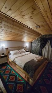 a bed in a room with a wooden ceiling at The Village House in Korçë