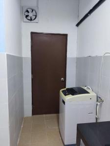 Un baño con una puerta marrón y una máquina. en Ruzimas Desaru Homestay, en Bandar Penawar