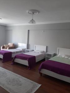 Habitación con 3 camas con sábanas moradas. en KESKINEL apart en Amasra