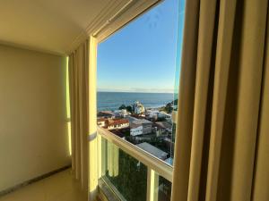 um quarto com uma janela com vista para o oceano em Apartamento Iriri Vista para o Mar em Iriri